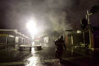 Un bombero abandona una zona comercial de la ciudad de Evreux, al oeste de Francia, aún humeante tras haber sido incendiada.