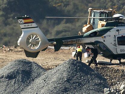 Un agente baja explosivos del helicoptero para los trabajos de excavación.