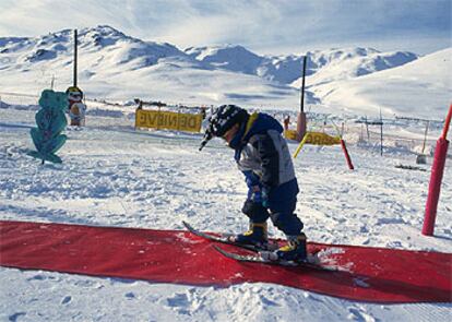 Un niño da sus primeros pasos con esquís en un jardín de nieve de Baqueira-Beret.