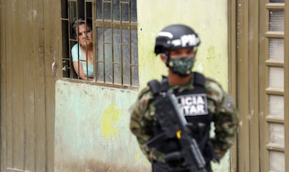 Una mujer observa desde su casa a un efectivo de la policía militar colombiana en el municipio de Soacha.