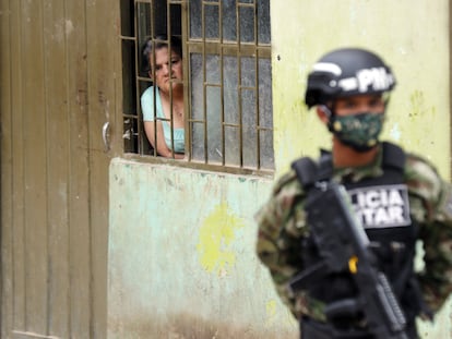 Una mujer observa desde su casa a un efectivo de la policía militar colombiana en el municipio de Soacha.