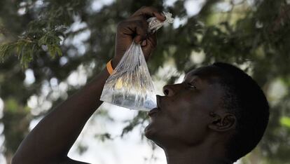 Un vendedor de agua bebe de una de sus bolsitas de plástico en la ciudad ribereña de Athi, en Kenia.