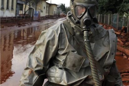 Un soldado húngaro, con un equipo de protección química, camina entre el barro rojo por una calle inundada de Devecser (Hungría).