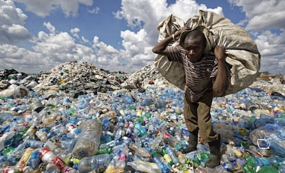 Homem enche uma sacola com plásticos em um lixão nos subúrbios de Nairóbi, Quênia.