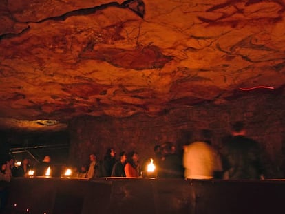 Visitantes en la neocueva de Altamira iluminada con lámaras de tuétano.