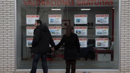Una pareja mira un escaparate con anuncios de pisos en el Ensanche de Vallecas (Madrid).