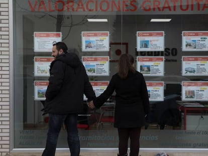 Una pareja mira un escaparate con anuncios de pisos en el Ensanche de Vallecas (Madrid).