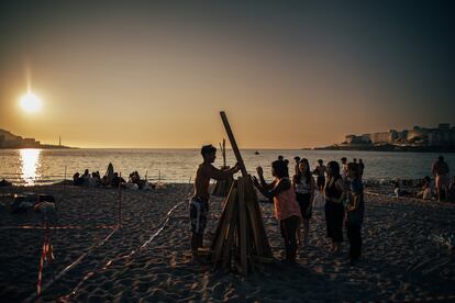 Un grupo de jóvenes prepara una de las hogueras en el espacio habilitado en la playa de Riazor, A Coruña.  