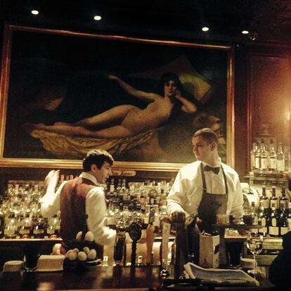 Dos camareros atienden una barra de bar.