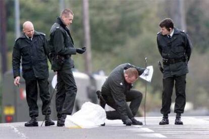 Policías de Irlanda del Norte buscan pruebas tras un atentado frente a una comisaría en Belfast, en el año 2000.