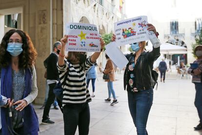 Dos mujeres sostienen pancartas de apoyo al menor de 8 años asesinado en la localidad alicantina de Elda mientras la acusada del homicidio entra en el juzgado.