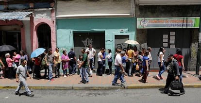 Vecinos de Caracas, Venezuela, hacen cola para comprar alimentos.