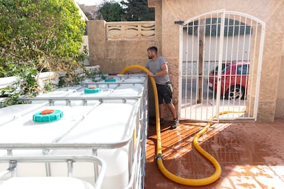 Un operario de una empresa de camiones cisterna rellena varias cubas de agua.