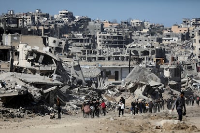 Varios palestinos se abren paso entre los escombros de casas y edificios destruidos, tras el alto el fuego entre Israel y Hamás, este martes en Jabalia.