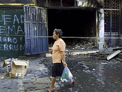 Una mujer pasa ante una tienda saqueada durante el fin de semana en Caracas.