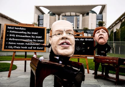 Activistas climáticos protestan con máscaras parecidas a la canciller alemana Angela Merkel (dcha) y el ministro de Economía alemán Peter Altmaier, frente a la Cancillería durante una reunión del Gabinete en Berlín, el 12 de mayo.