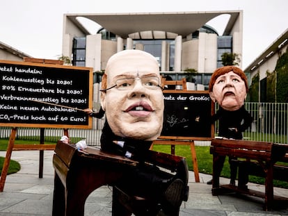 Activistas climáticos protestan con máscaras parecidas a la canciller alemana Angela Merkel (dcha) y el ministro de Economía alemán Peter Altmaier, frente a la Cancillería durante una reunión del Gabinete en Berlín, el 12 de mayo.