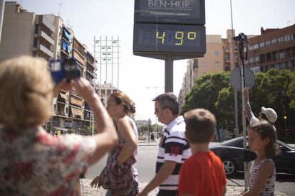 Una mujer fotografía el termómetro de Plaza de Armas (Sevilla) que llegó a marcar 49 grados centígrados.