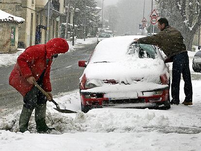 Dos hombres retiran la nieve acumulada ayer sobre las calles y vehículos de la localidad alavesa de Murgia.