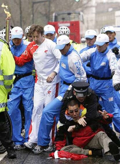 Un policía reduce a un manifestante que intentaba acercarse a la antorcha, custodiada por policías chinos.