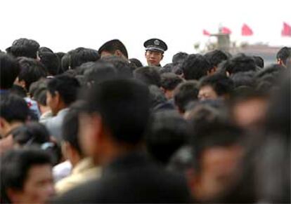 Un policía entre la multitud en la estación de Tiananmen de Pekín al inicio de las vacaciones del Primero de Mayo.