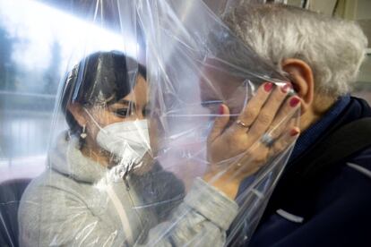 Una mujer con mascarilla acaricia a una anciana a través de una cortina especial, en una residencia de Roma (Italia). Las autoridades italianas aseguraron hoy que la candidata a vacuna creada íntegramente en el país ha demostrado ser segura en la fase 1 e inducir una respuesta inmune en humanos, y han subrayado que presentarán el protocolo a las agencias reguladoras del medicamento próximamente.