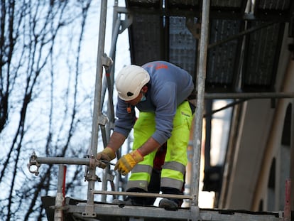 Un obrero de la construcción trabaja sobre un andamio en una calle en Madrid.