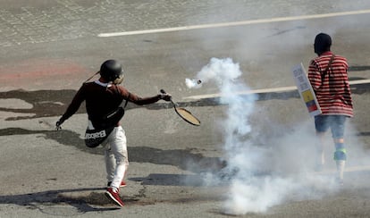 Un manifestante de la oposición utiliza una raqueta de tenis para devolver un bote de gas lacrimógeno a la policia antidisturbios.