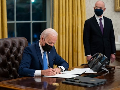 El secretario de Seguridad Nacional Alejandro Mayorkas acompaña al presidente Joe Biden mientras firma una orden ejecutiva en la Casa Blanca.