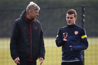 Wilshere charla con Wenger.