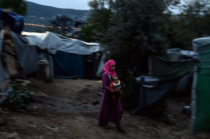 Una mujer migrante sostiene a su bebé mientras camina en un campo de refugiados en la isla griega de Samos. El campamento de Samos, originalmente construido para albergar a 650 personas, ha superado tales límites.