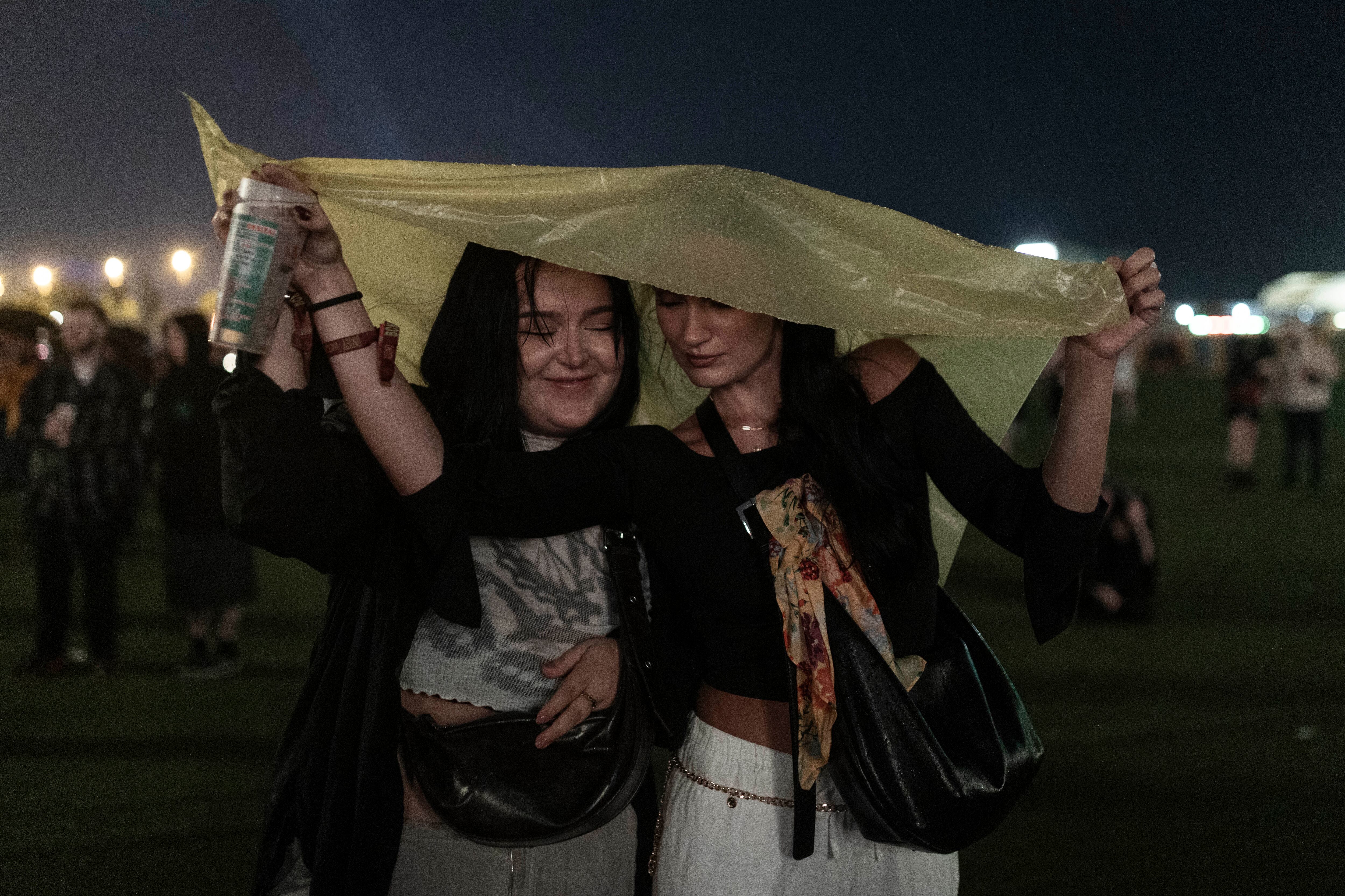 Asistentes en el festival siguen bajo la lluvia el concierto de PJ Harvey.   