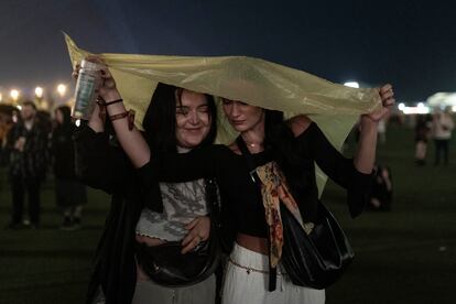 Asistentes en el festival siguen bajo la lluvia el concierto de PJ Harvey.