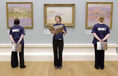 Tres guías con camisetas y catálogos de la exposición de Monet, ante tres cuadros del pintor en la Real Academia Escocesa.