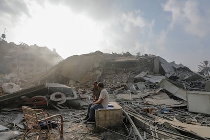 Dos personas permanecen sentadas junto a los escombros de la torre Al Watan, en la ciudad de Gaza, destruida tras un ataque israelí, este domingo. 