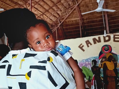 Una niña en brazos de su madre durante una sesión del proyecto de formación Fandema, en Tujereng (Gambia).