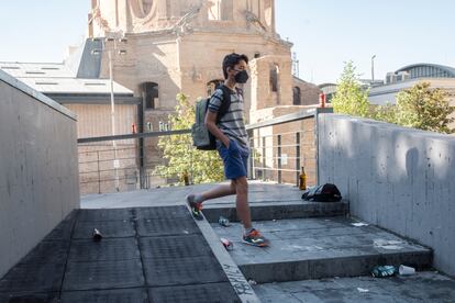 Un adolescente pasa por una escalera de bajada a la plaza de Agustín Lara, en Lavapiés, donde se acumula la basura.