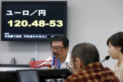 Trabajadores de un corretaje de moneda extranjera operan junto a una pantalla en la que se observa el cambio del yen japonés frente al euro, en Tokio. EFE/Archivo