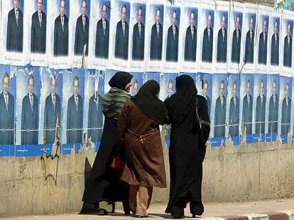 Tres mujeres argelinas caminan por una calle de Argel, junto a un muro con carteles de la campaña electoral del actual presidente argelino, Abdelaziz Bouteflika.