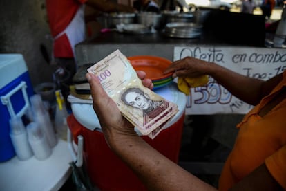 Una mujer paga con un billete de 100 bolívares en un restaurante ambulante en Catia (Venezuela), el 12 de diciembre de 2016, tras el decreto de emergencia del presidente Nicolás Maduro en el cual dictaminó que el billete de esta denominación sería puesto fuera de circulación a finales de ese mismo mes. En julio de 2018, el Fondo Monetario Internacional (FMI) proyectó una inflación de 1.000.000% para el cierre del año en Venezuela. Alejandro Werner, economista en el FMI a cargo del departamento que sigue la evolución de los países de la región latinoamericana, comparó la situación del país con la Alemania de 1923 o Zimbabue de 2008, una economía en la que los precios están descontrolados y el dinero pierde valor a una velocidad exponencial, acompañado del desplome de la demanda. Con un cambio no oficial que rige la divisa, el salario mínimo en Venezuela está fijado en 1,5 dólares al mes. Antes de la reconversión monetaria promovida por el Gobierno de Nicolás Maduro en agosto, que dio entrada al bolívar soberano, el billete de mayor denominación era el de 100.000 bolívares, cantidad que alcanzaba para pagar una fotocopia o comprar un huevo.