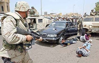 Un policía militar estadounidense apunta con su arma a iraquíes detenidos por saqueo en el centro de Bagdad.