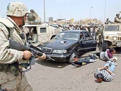 Un policía militar estadounidense apunta con su arma a iraquíes detenidos por saqueo en el centro de Bagdad.