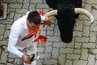 Un mozo seguido muy de cerca por uno de los astados de Jandilla, durante el sexto encierro de los sanfermines.