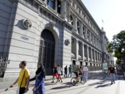 Varios transeúntes caminan por la madrileña calle de Alcalá, junto al edificio del Banco de España.