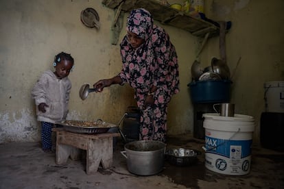 La pequeña Sunje mira entusiasmada la comida que su madre, Fatumata Cissé, está preparando para ellas y otros compañeros en el barrio de Cinema en Nuadibú. 