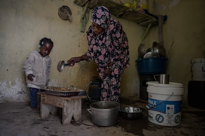 La pequeña Sunje mira entusiasmada la comida que su madre, Fatumata Cissé, está preparando para ellas y otros compañeros en el barrio de Cinema en Nuadibú.