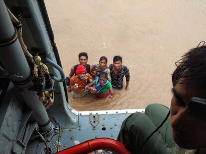 Un grupo de habitantes espera a ser rescatado por los servicios de emergencia tras las fuertes lluvias que provocaron inundaciones, cerca de Ahmedabad (India).