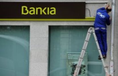 Un trabajador instala el logotipo de Bankia en una de las oficinas de la entidad.