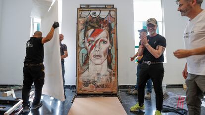 El artista Jesús Arrúe (segundo ala derecha), asiste a la instalación del grafiti de David Bowie, en L'Etno.