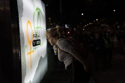 Una mujer realiza una pinta con un símbolo feminista en un anuncio publicitario.